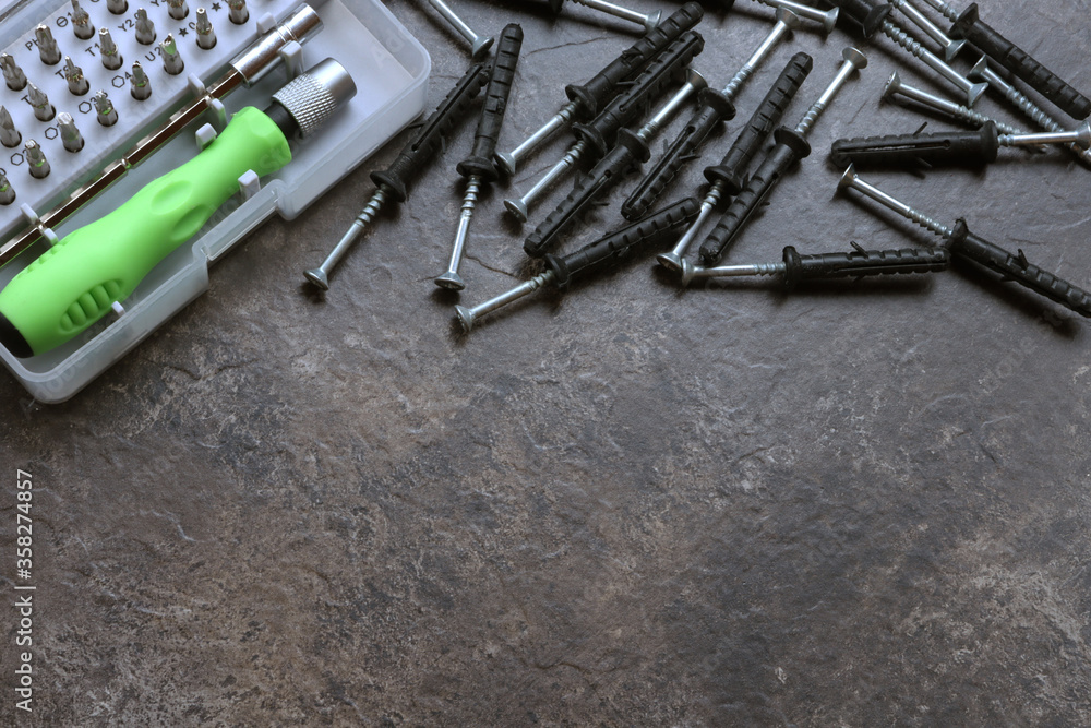 Screws, screwdriver and bits for screwdriver on a brown embossed background with place for text. Screws with place for design and text. Screws, screwdriver and bits for screwdriver on a brown embossed background with place for text. Screws with place for design and text.
