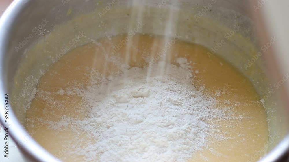 Preparation of yeast dough. Female hand pours flour and mixes baking ingredients Preparation of yeast dough. Female hand pours flour and mixes baking ingredients