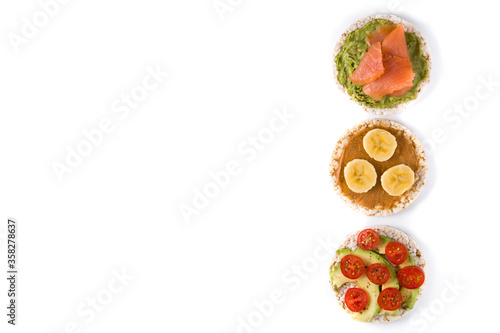 Assortment of ingredients on puffed rice cakes isolated on white background. Top view. Copy space