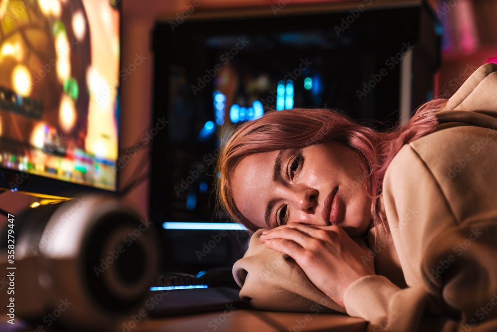 Image of exhausted attractive girl lying on table while playing video