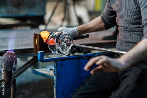 Hot molten glass material finished by the hands of a glass craftsman. Beautiful image inside a glass factory where glass objects are handmade. Labour day. 