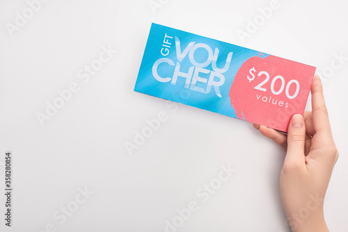 Fotografie Top view of woman holding gift voucher with 200 values lettering on white backgr
