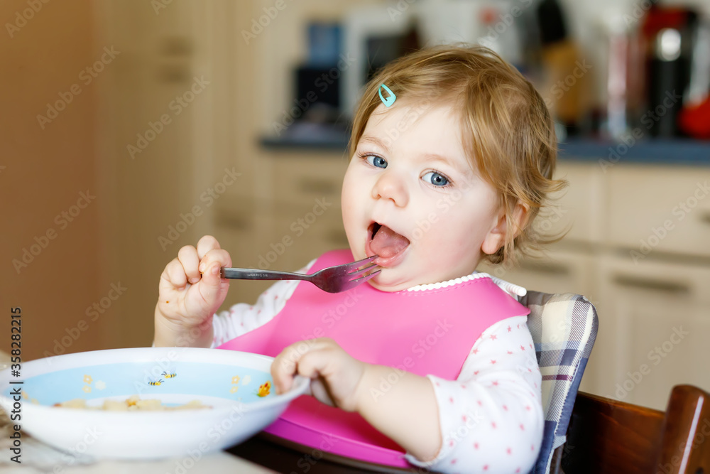 Adorable baby girl eating from spoon mashed vegetables and puree. food, child, feeding and people concept Adorable baby girl eating from spoon mashed vegetables and puree. food, child, feeding and people concept