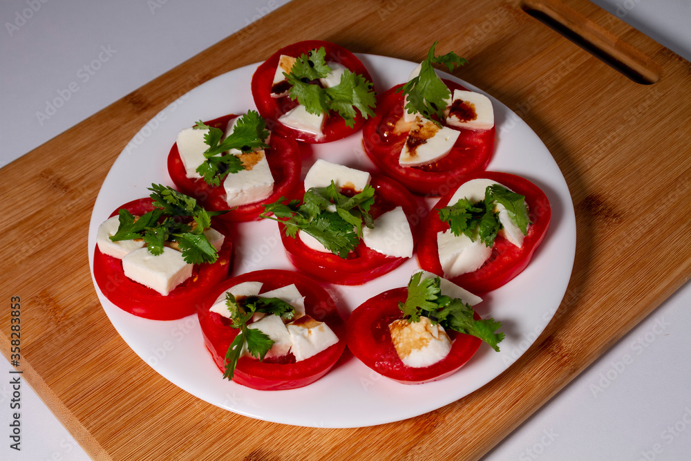 Antipasti. Tomatoes, mozzarella cheese, basil and balsamic vinegar on a white plate. The concept of vegetarian food. Antipasti. Tomatoes, mozzarella cheese, basil and balsamic vinegar on a white plate. The concept of vegetarian food.