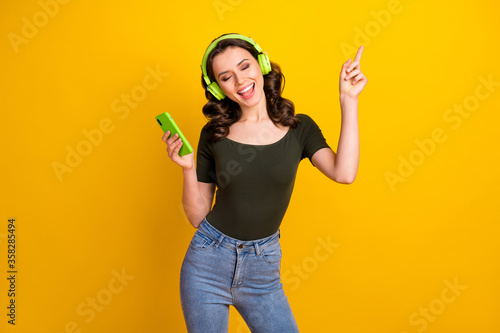 Portrait of her she nice attractive lovely pretty dreamy cheerful cheery wavy-haired girl enjoying listening music having fun dancing isolated on bright vivid shine vibrant yellow color background
