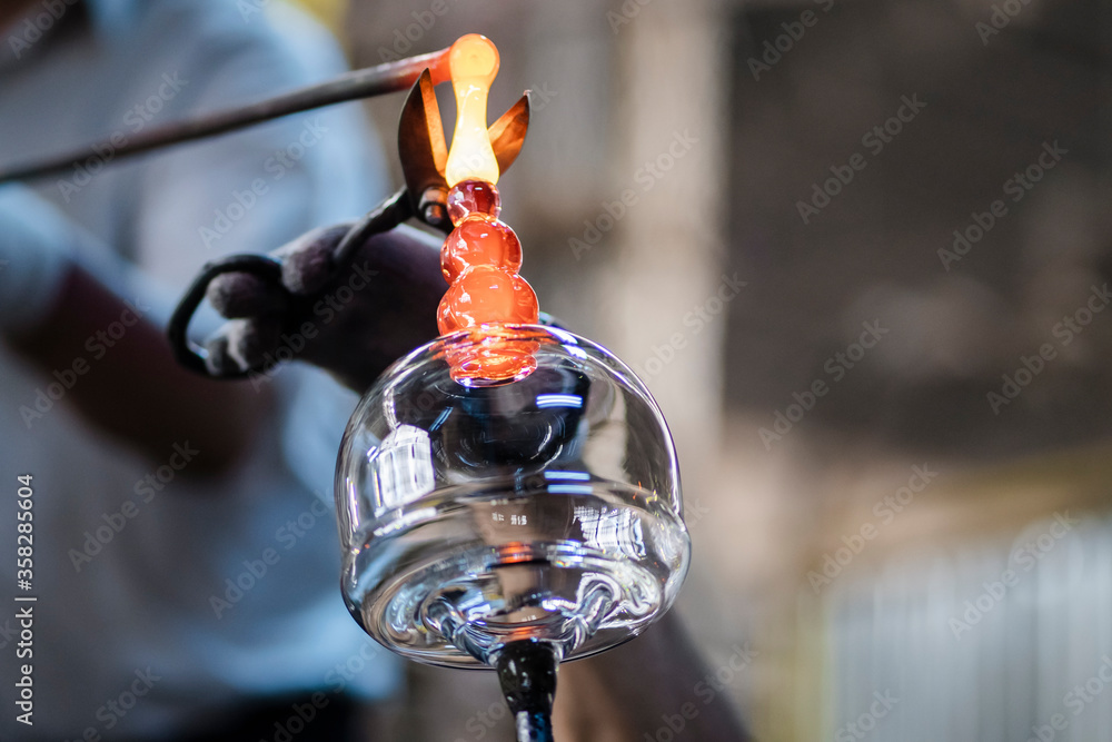 Glassblower artist working in a glass factory where products are created manually. The art of handmade glass products. Hot molten glass manually poured by the craftsmen. Arts and crafts. Glassblower artist working in a glass factory where products are created manually. The art of handmade glass products. Hot molten glass manually poured by the craftsmen. Arts and crafts.