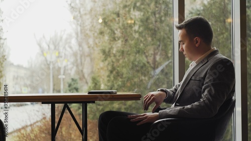 Handsome man waiting woman in restaurant and watching to clock