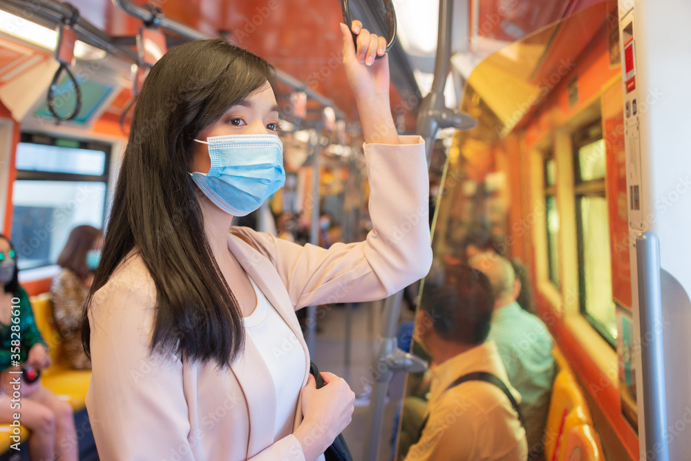 Asian woman in a protective mask or surgical mask standing in a train