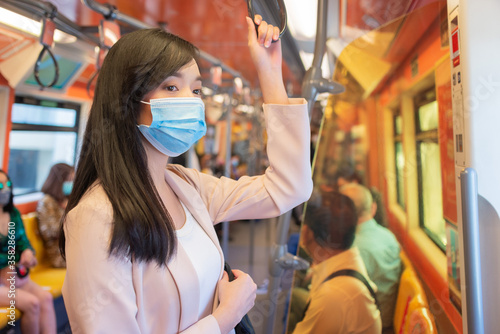Asian woman in a protective mask or surgical mask standing in a train