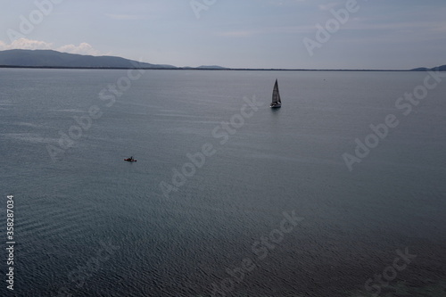 Barca a vela naviga verso l'orizzonte in una mare calmo - Talamone - Toscana - Italia