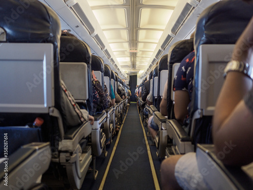 The cabin of the plane, the seated passengers in the corridor.