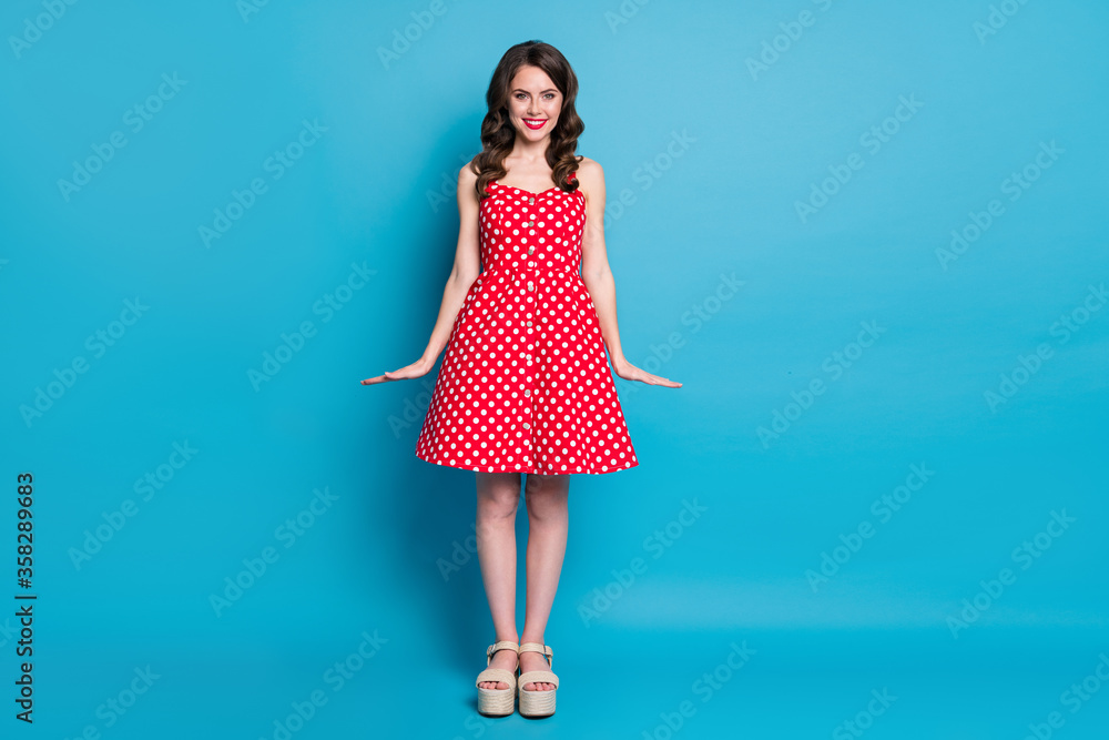 Full size photo of attractive pretty curly lady shiny pomade smiling white teeth good mood flirty wear summer red white dotted retro dress open toes shoes isolated blue color background Full size photo of attractive pretty curly lady shiny pomade smiling white teeth good mood flirty wear summer red white dotted retro dress open toes shoes isolated blue color background