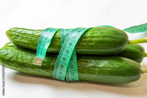 Three fresh cucumbers and measuring tape. Diet and Healthy life, loss weight concept. Isolated. White background