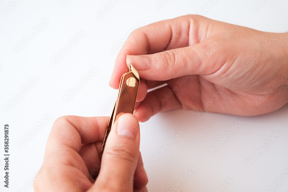 Woman hands using a nail clippers to cut her fingernails on a white background. View from above. Manicure at home