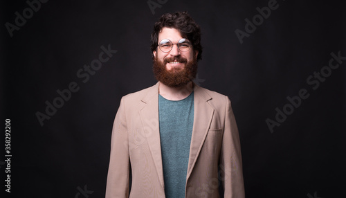 Photo of smiling bearded man in suit standing over black background © Vulp