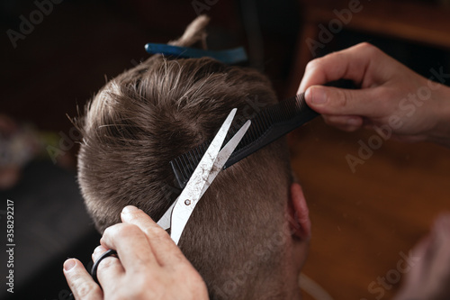 hand cutting hair with a comb and scissors.hairdresser makes fashionable hairstyle to client