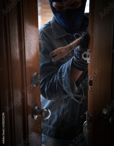 burglar holding Lock-picker to open a housedoor photo