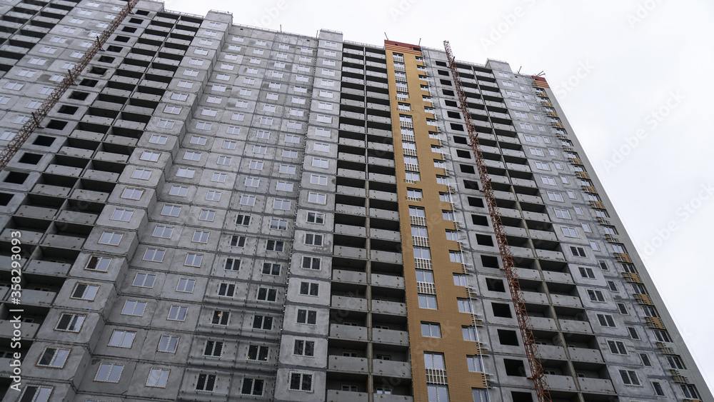 Large construction site on a background of blue sky. Brick, panel apartment building. Industrial theme for design Large construction site on a background of blue sky. Brick, panel apartment building. Industrial theme for design