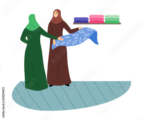 Canvas Print Muslim girls in a traditional ethnic hijab choose fabrics in the store
