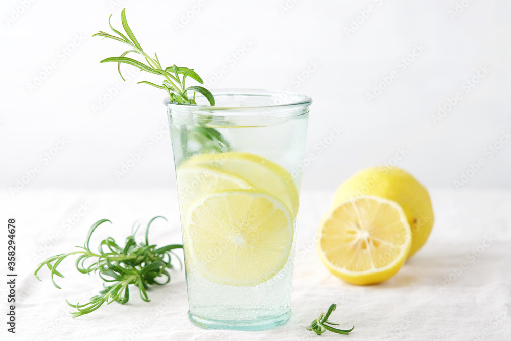 Lemon with rosemary summer cocktail or lemonade. Cold refreshment non-alcohol drink with lemon in glass Lemon with rosemary summer cocktail or lemonade. Cold refreshment non-alcohol drink with lemon in glass