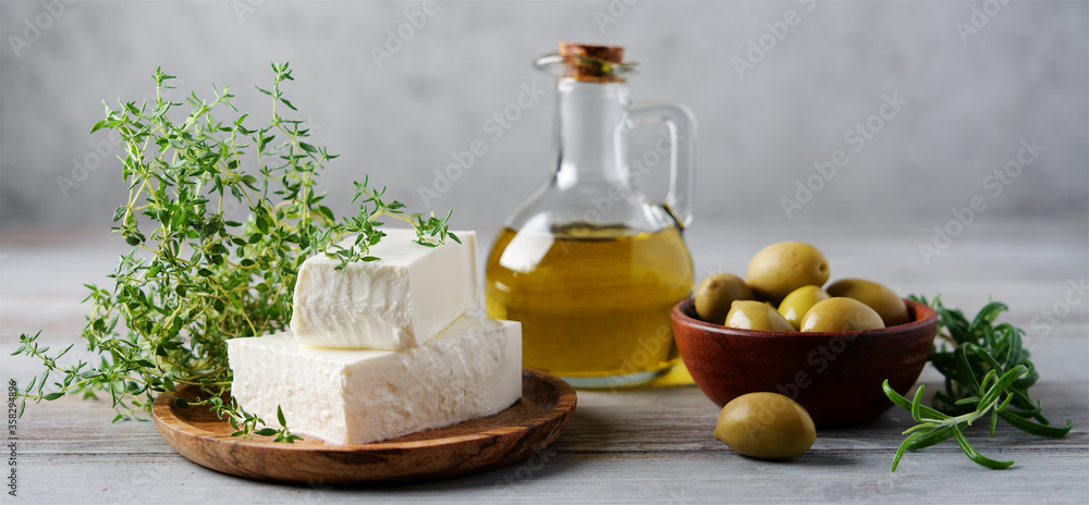 Soft feta cheese on wooden plate with olive oil, olives and thyme. Traditional Mediterranean Food Ingredients Soft feta cheese on wooden plate with olive oil, olives and thyme. Traditional Mediterranean Food Ingredients