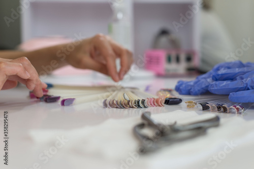 Choice of color of nails. a young girl of twenty-seven years old chooses a color for nails in a beauty salon. beauty and health of nails. Color and painting of manicure