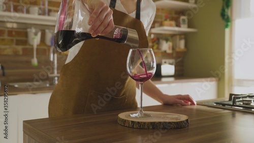 Woman pours a glass of red wine in luxury house