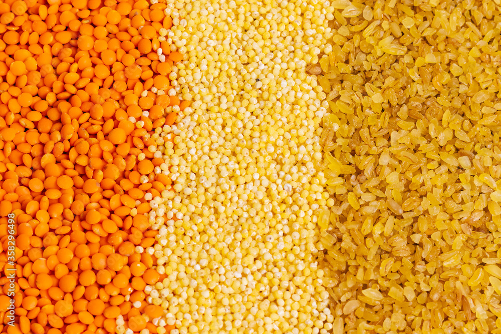 Raw orange lentils, millet and bulgur for proper nutrition and health on a gray background