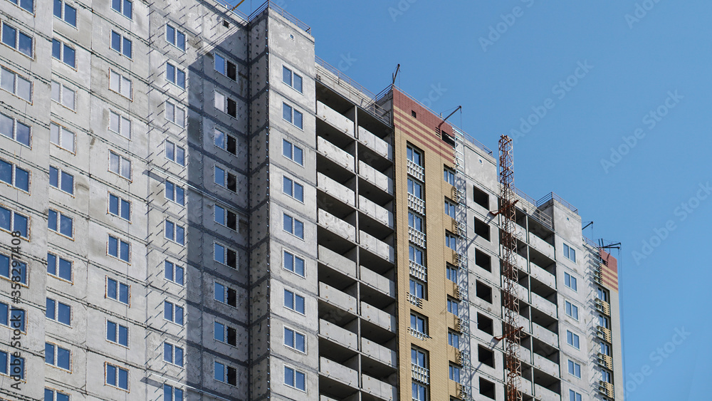 Fototapeta premium Large construction site on a background of blue sky. Brick, panel apartment building. Industrial theme for design