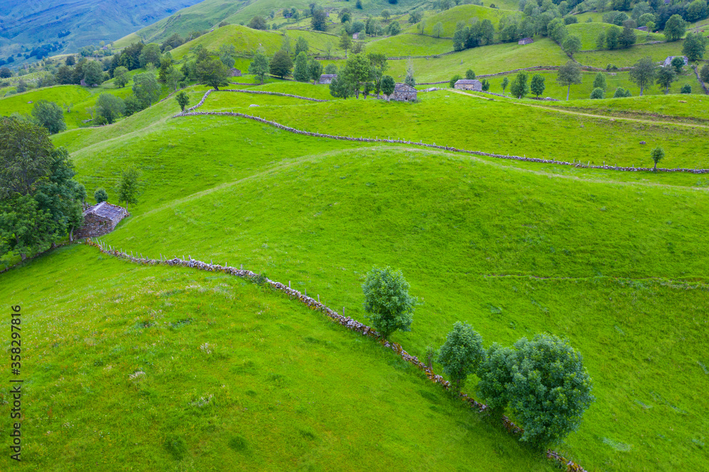 Obraz premium Aerial view with a drone of the spring landscape of pasiegas cabins and meadows in the Miera Valley in the Autonomous Community of Cantabria. Spain, Europe