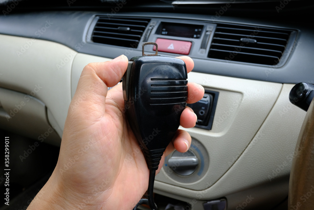 Hand holding microphone walkie-talkie radio communication in car