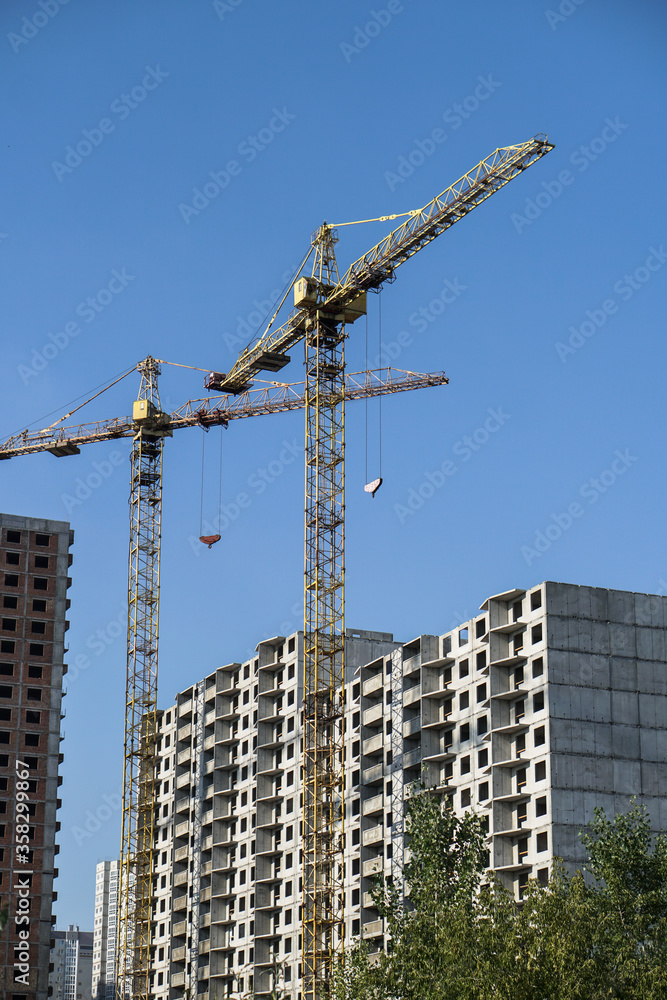 Multi-stage construction during the construction process with a yellow crane. Industrial background for design.