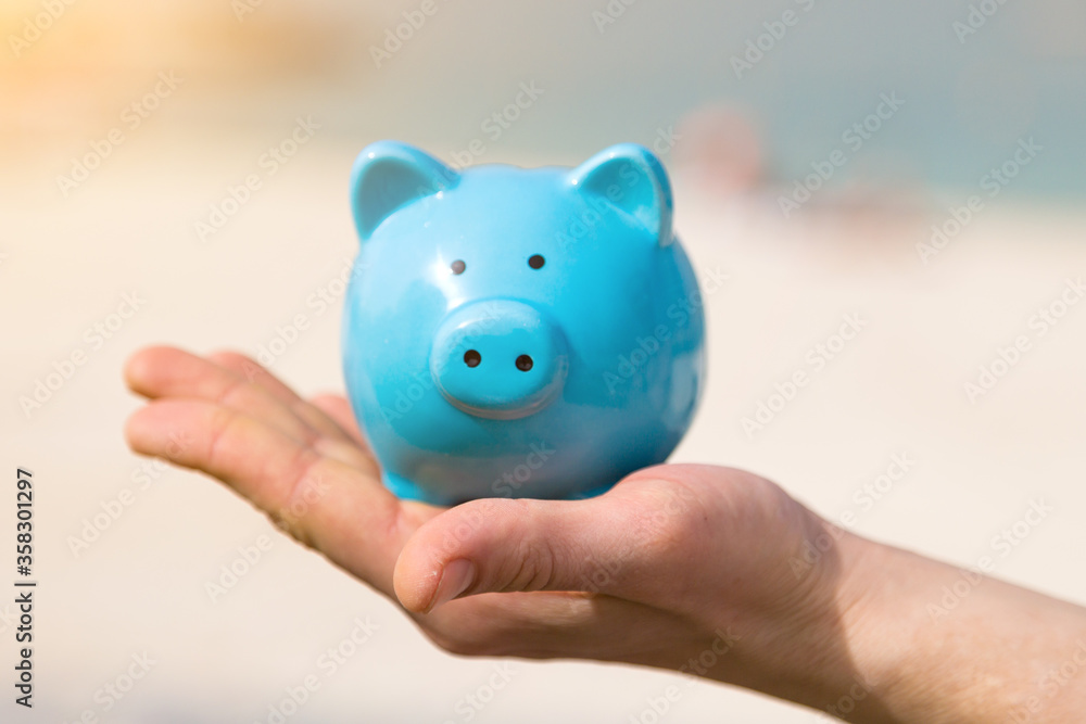 A man holds a piggy bank in his hand on his vacation A man holds a piggy bank in his hand on his vacation by the sea