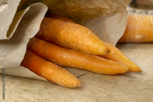 Fresh organic carrots in recyclable bag on wooden table. Healthy food, vegetarian, paleo diet, agriculture. Vegetables from super market.