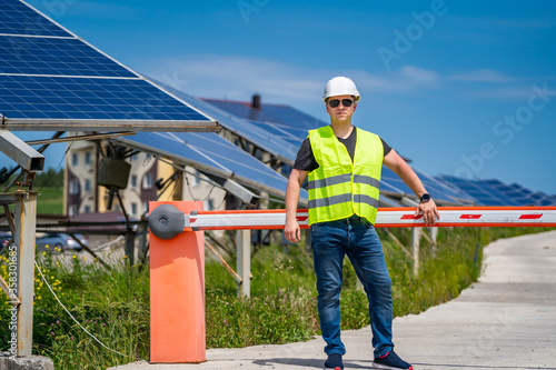 Worker in new energy base farm. Engineering technician on solar pannels background.