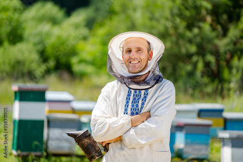 The beekeeper stands crosshands near apiary. Apiculture. Apiary. photo