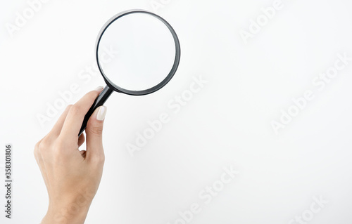 image of spying woman's hand holding magnifying glass on isolated white background