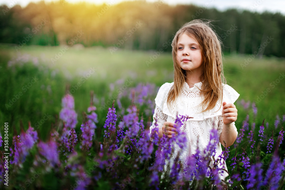 A little girl in a white dress with beautiful flowers in the field in summer. Concept of happy childhood. Copy space for text A little girl in a white dress with beautiful flowers in the field in summer. Concept of happy childhood. Copy space for text