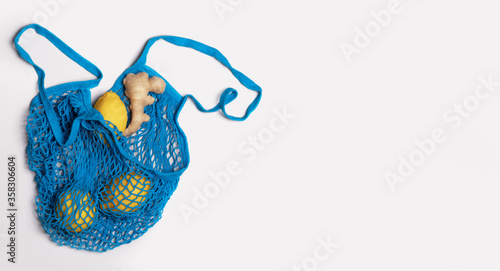 Blue shopper grid with shopping citruses lemons and ginger on a light gray background. Shopping bag reusable, eco friendly concept, zero waste, recycling. Isolated. Social environmental responsibility