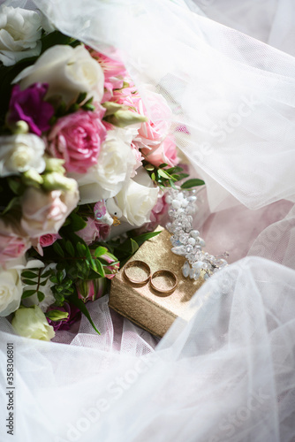 Elegant wedding accessories of an attractive bride. Wedding rings  shoes  bridal bouquet  floral arrangements  veil. Copy space for text. Background for greeting card or invitation.