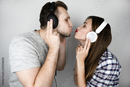 young couple man in black headphones woman in white headphones kissing each other on isolated white background, love and music concept photo