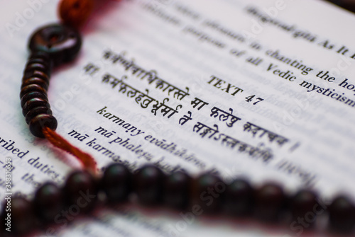 A text from Hindu sacred book Bhagavad Gita along with rosary.