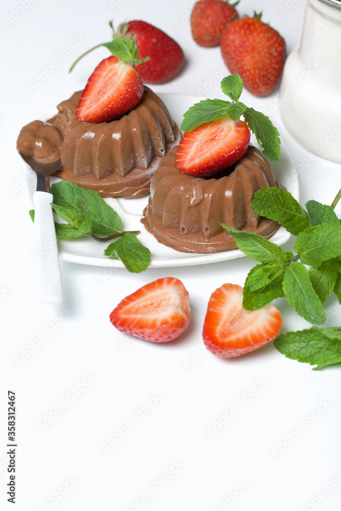 Chocolate fudge garnished with half a strawberry with petals. Garnished with sprigs of mint and strawberries. On the white surface of the table. Chocolate fudge garnished with half a strawberry with petals. Garnished with sprigs of mint and strawberries. On the white surface of the table.