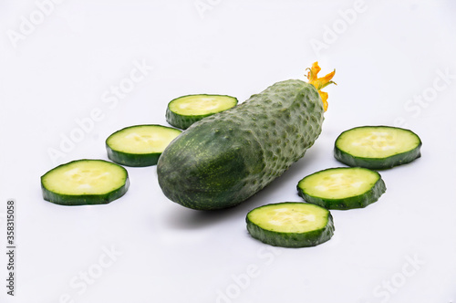 Fresh tasty wholesome cucumber and cut slices lie on a white background.