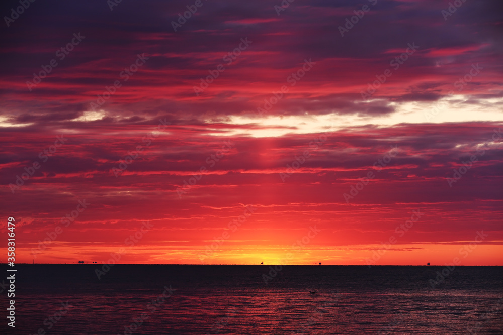 Colorful red sunset sunrise at sea. Water and sky. Minimalism in nature. Dark photo at dusk. Sea landscape.