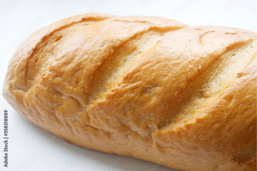 A loaf of fresh white bread, with a crust, on a light background. Bread texture, homemade cakes, cooking, breakfast, bakery. Rise in price, raise food prices