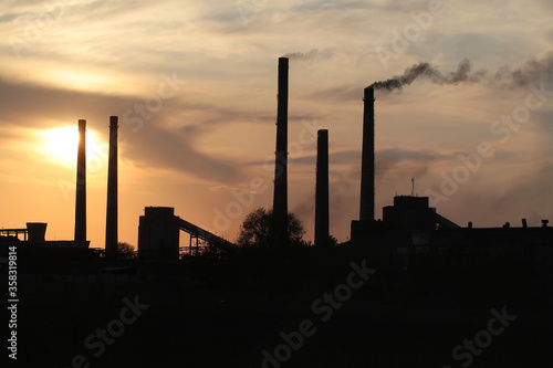 .Smoking chimneys of a plant against the setting sun