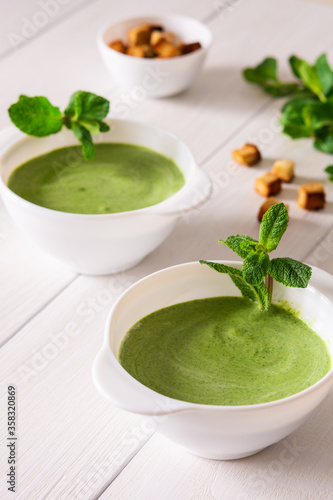Delicious fresh cream soup of young peas and mint with croutons made of white bread, healthy food