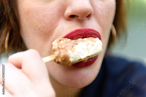 Female mouth eating ice cream on the natural background. Finished ice cream