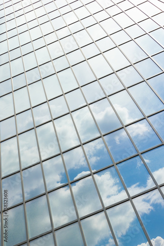 Clouds reflected in windows of modern office building. Facade texture of a glass mirrored office building.